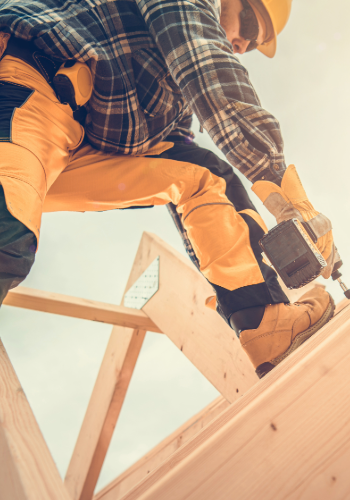 Professional roofing contractor working on a roof installation with precision tools under sunny conditions.