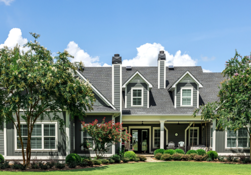 Beautiful residential home with a newly replaced gray shingle roof, surrounded by lush greenery and a well-manicured lawn.