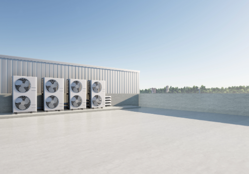 Commercial building rooftop with multiple air conditioning units, showcasing a newly replaced flat roof under clear skies.